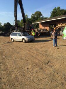 A silver minivan parked at the salvage yard with a large crane in the background at Queen City Metal Recycling & Salvage in Charlotte, NC.