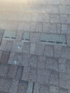 A section of a shingled roof with missing shingles, exposing the underlayment, a repair service by Dan's "Do it All" Handyman Services in Reno, NV.