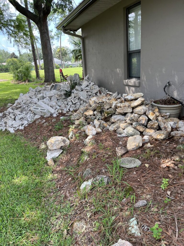 A mixed pile of concrete and rock debris next to a house, ready for general junk removal by DUMP 4 U Hauling in Jacksonville, FL.