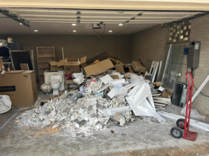 A large pile of mixed construction and household debris inside a garage for removal by NICOS Hauling in San Diego, CA.