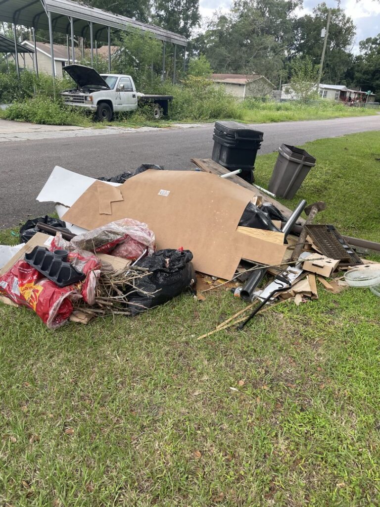 A large pile of mixed junk and debris on a grassy area, ready for removal by Junk Removal JAX in Jacksonville, FL.