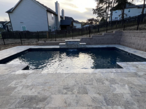 A modern backyard pool with a stone waterfall and retaining wall, expertly built by Southern Pool Solutions in Knoxville, TN.