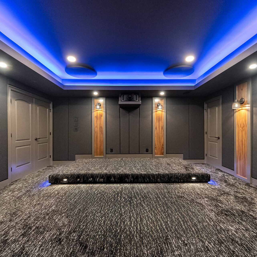 Modern basement home theater with dark walls, accent lighting, and acoustic panels by BasementRemodeling.com in Rockville, MD.