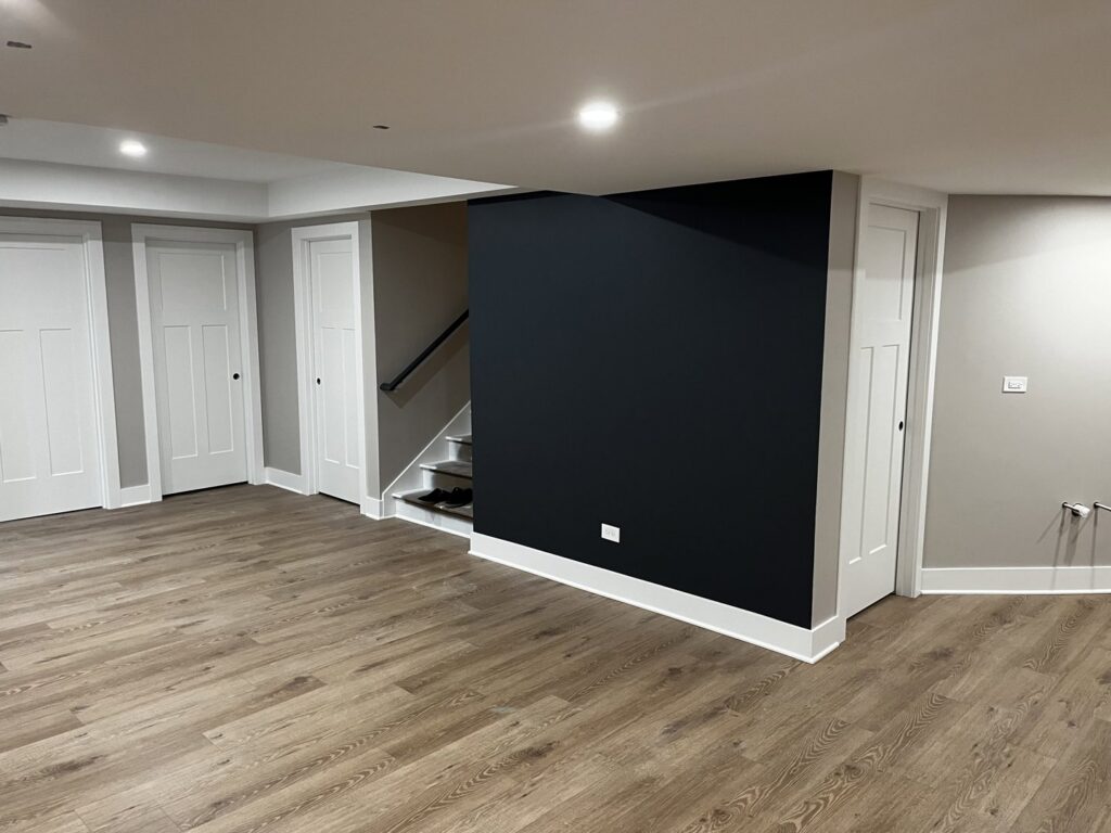 Modern basement remodel with a dark accent wall and new flooring by Silhouette Builders, Inc. in Yorkville, IL