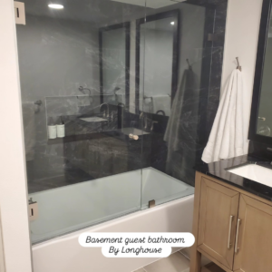 A modern basement guest bathroom featuring a bathtub and glass shower screen, completed by Longhouse Construction Inc. in Estacada, OR.