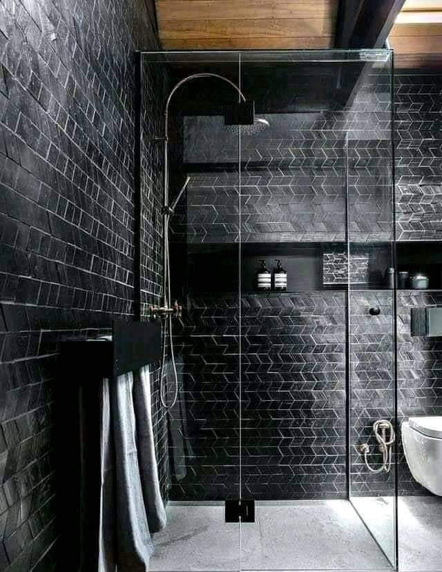 A modern bathroom featuring a black tiled shower and glass enclosure by Just Us Construction Inc in Philadelphia, PA.