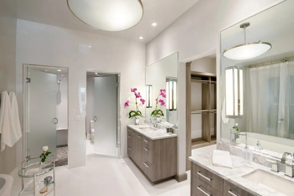 A modern bathroom remodel with a double vanity and glass shower doors by Kornerstone Kitchens in Orlando, FL.