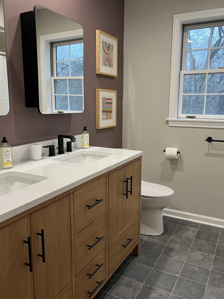 A modern bathroom featuring a double vanity, large mirror, and tiled floor by Santoro Home Improvements in Wallingford, CT.