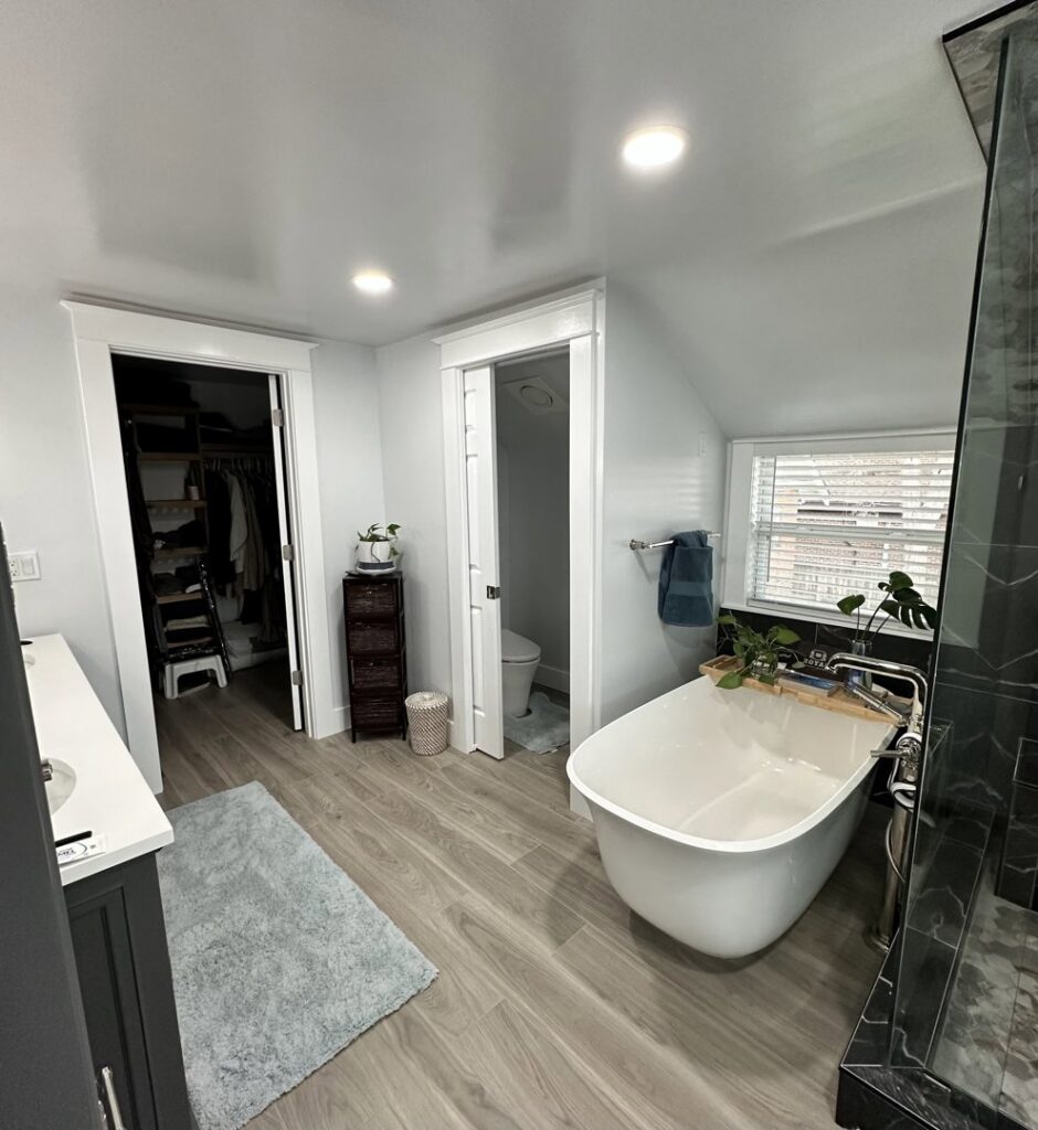 A modern bathroom featuring a sleek freestanding tub, vanity, and closet, renovated by RAW Renovation in Denver, CO.