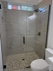 A modern bathroom featuring a newly installed glass shower enclosure and tiled walls by Dahlman Construction in San Tan Valley, AZ.
