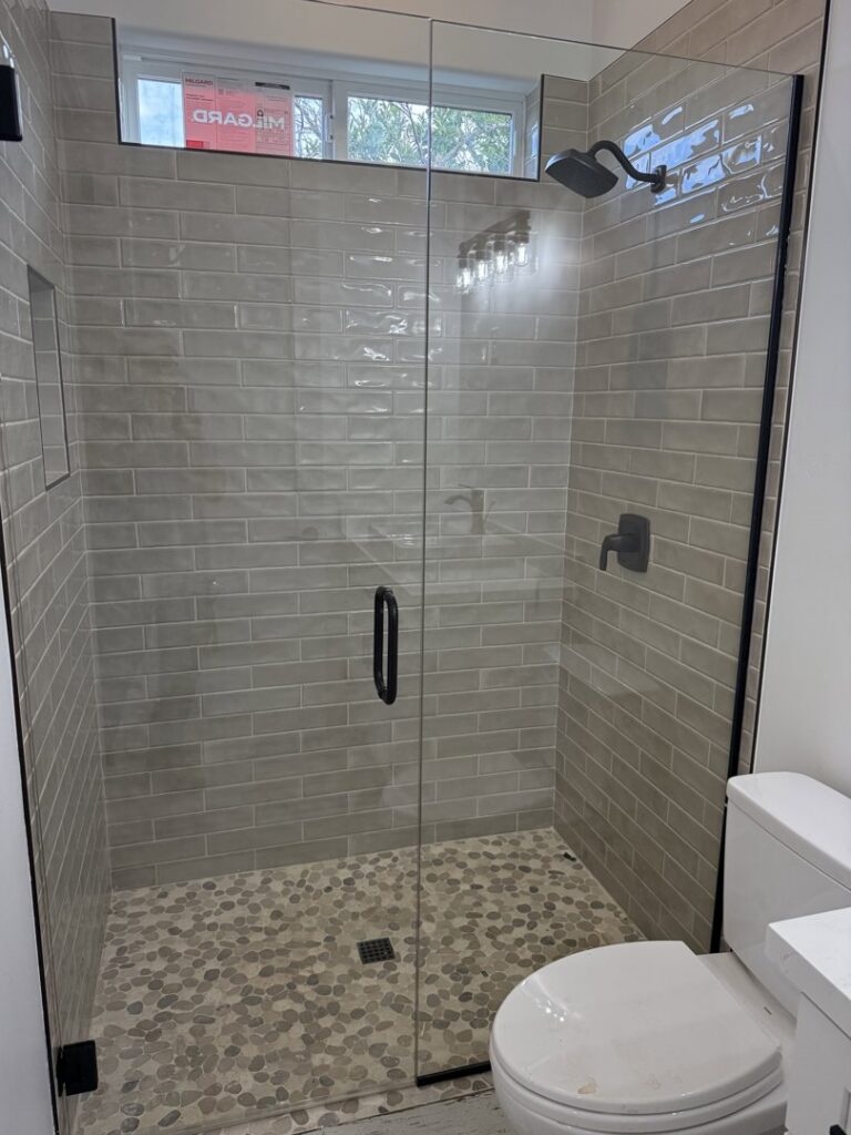 A modern bathroom featuring a newly installed glass shower enclosure and tiled walls by Dahlman Construction in San Tan Valley, AZ.