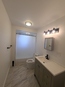 A modern bathroom featuring grey tiled floors and a new vanity, completed by Modern Image Construction LLC in El Paso, TX