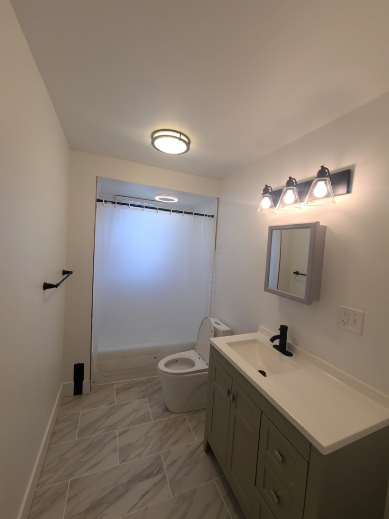A modern bathroom featuring grey tiled floors and a new vanity, completed by Modern Image Construction LLC in El Paso, TX