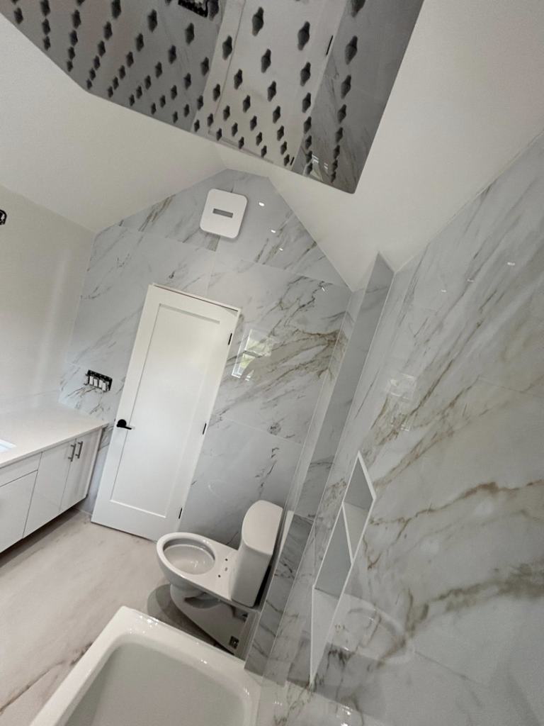 A modern bathroom with marble-tiled walls and new fixtures installed by Golden Tile Construction in Yonkers, NY.