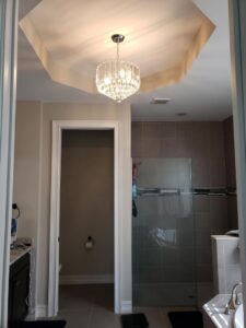 A beautifully remodeled modern bathroom featuring a chandelier and tiled shower by SouthCove Electric, LLC in Cape Coral, FL.