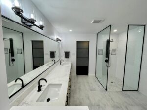 A modern bathroom remodel with a double vanity, large mirror, and walk-in glass shower by NP General Contracting in Austin, TX.