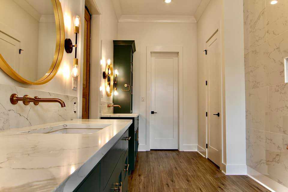 A modern bathroom remodel featuring a double vanity with marble countertops and new lighting by Regal Remodelers in Baton Rouge, LA.