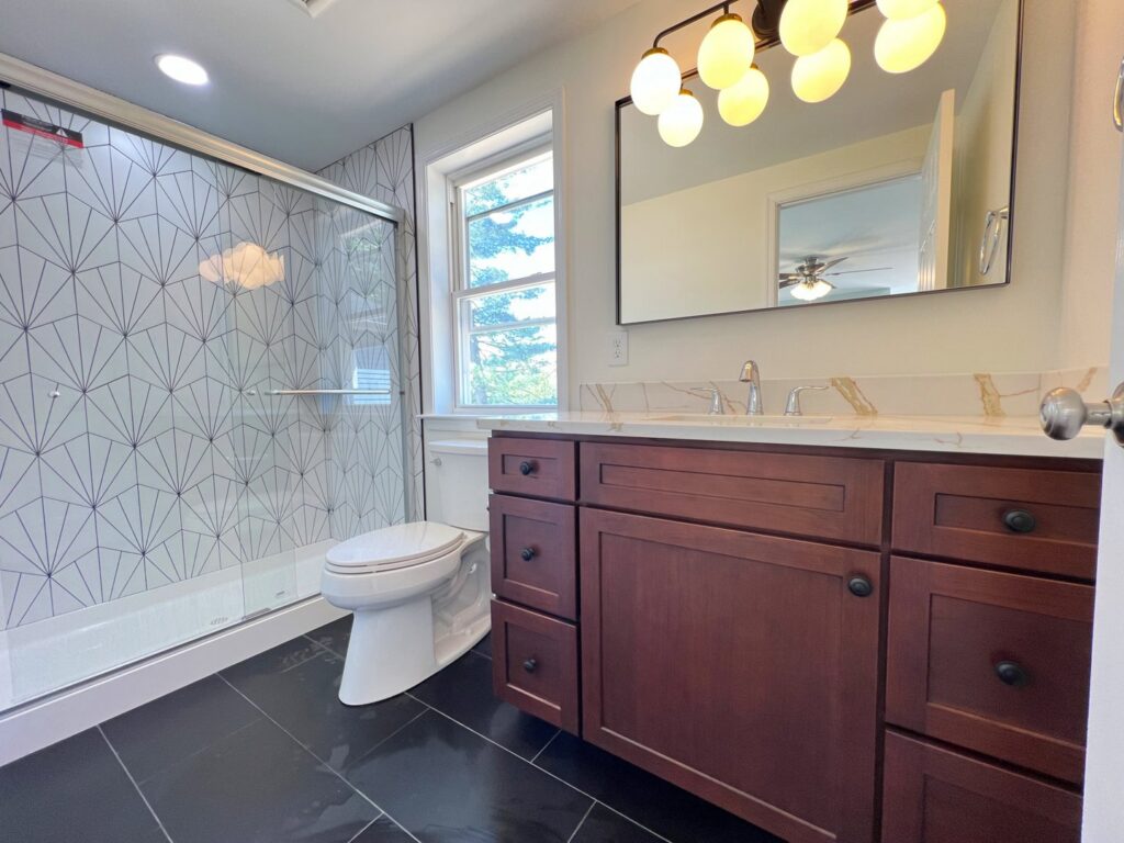 A modern bathroom remodel featuring a walk-in shower with geometric tiles by Dream Design Build & Remodeling, Inc. in Baltimore, MD