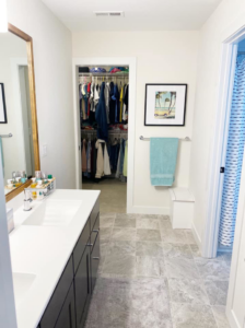 A modern bathroom remodel featuring a double vanity, tiled floor, and a spacious closet by KLS Remodel in Cincinnati, OH.