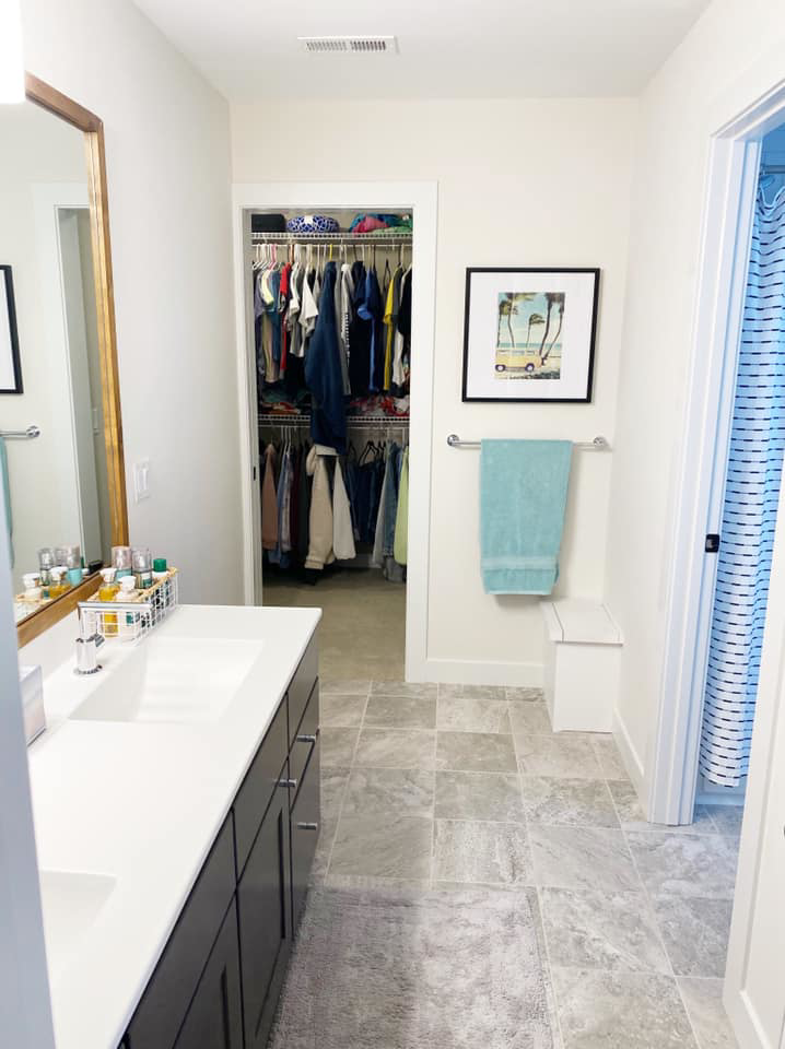 A modern bathroom remodel featuring a double vanity, tiled floor, and a spacious closet by KLS Remodel in Cincinnati, OH.