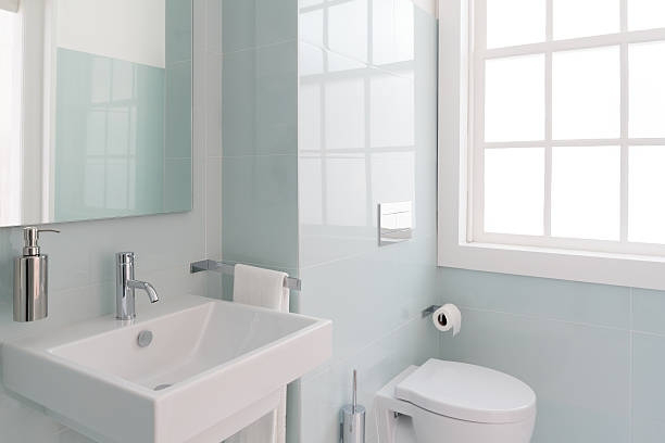 A modern bathroom remodel featuring a white sink, toilet, and light blue wall tiles by North Shore Kitchens in Pittsburgh, PA.