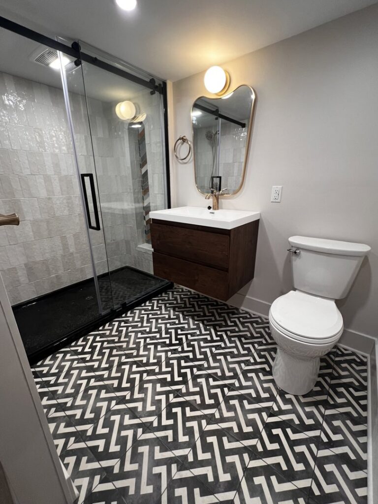 A modern bathroom remodel featuring striking patterned floor tiles and a floating vanity by DeShong Design + Remodeling in Pittsburgh, PA.