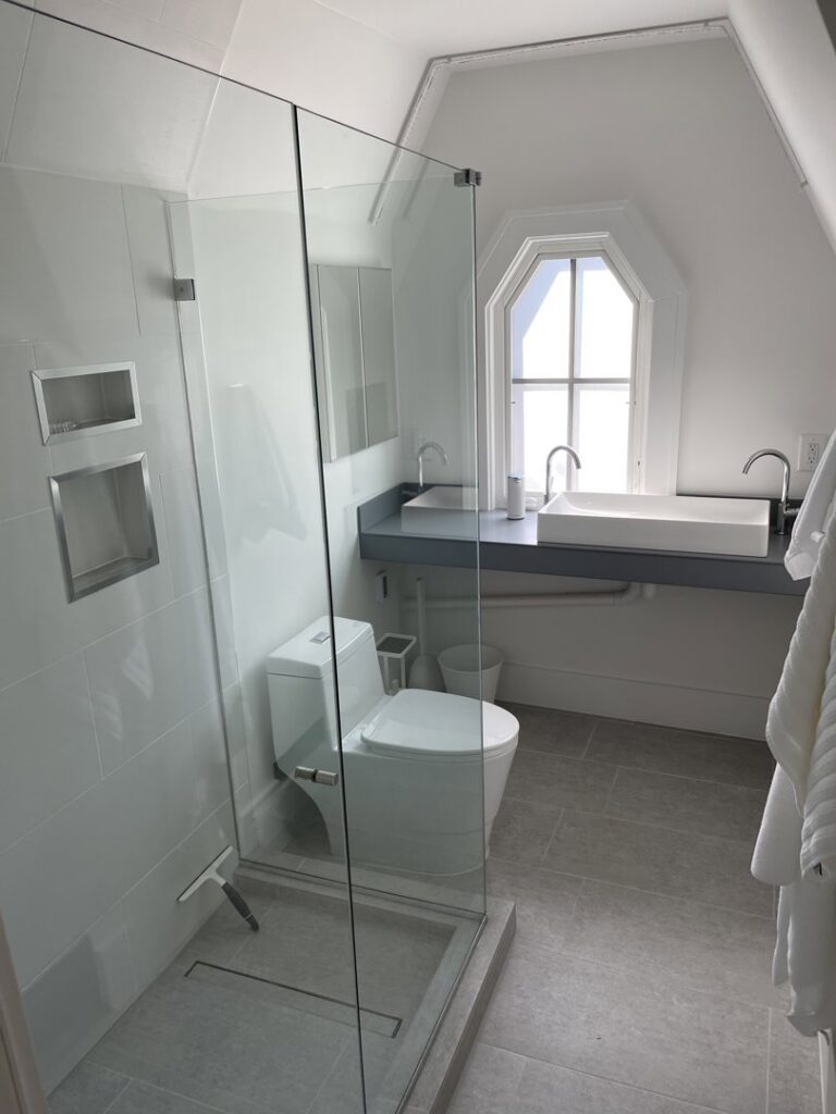 A completed modern bathroom remodel featuring a glass shower and double vanity by S-Squared Construction in Madison, WI.