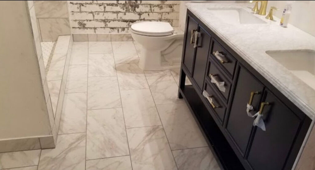 A modern bathroom remodel featuring new tile flooring, a dark vanity, and a toilet by Will.B.More Handyman & Remodel in West Jordan, UT