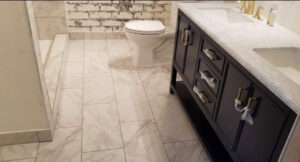 A modern bathroom remodel featuring new tile flooring, a dark vanity, and a toilet by Will.B.More Handyman & Remodel in West Jordan, UT