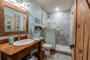 A modern bathroom remodel featuring a custom wooden vanity and a tiled walk-in shower by GCU Custom Builders in Louisville, KY.