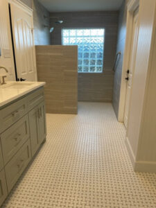 A modern bathroom remodel with a large vanity, tiled floor, and walk-in shower by MC Master Construction in League City, TX