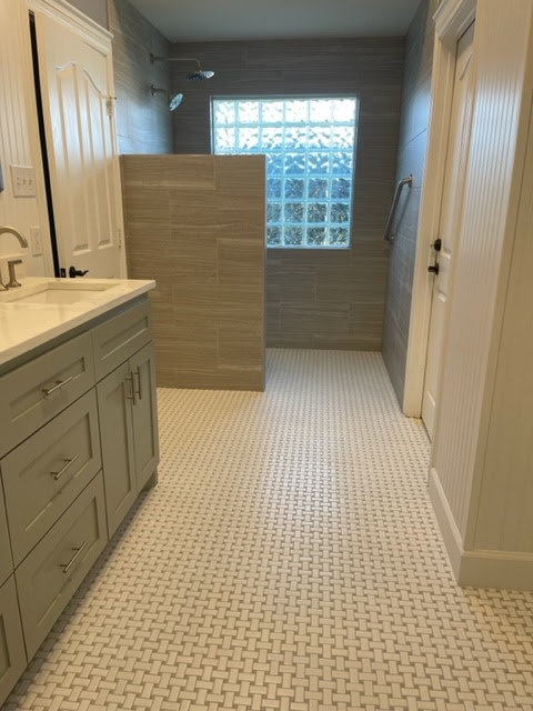 A modern bathroom remodel with a large vanity, tiled floor, and walk-in shower by MC Master Construction in League City, TX