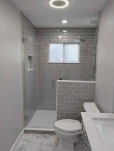 A modern bathroom remodel featuring a tiled walk-in shower, toilet, and vanity completed by McCollister Contracting LLC in New Castle, DE.