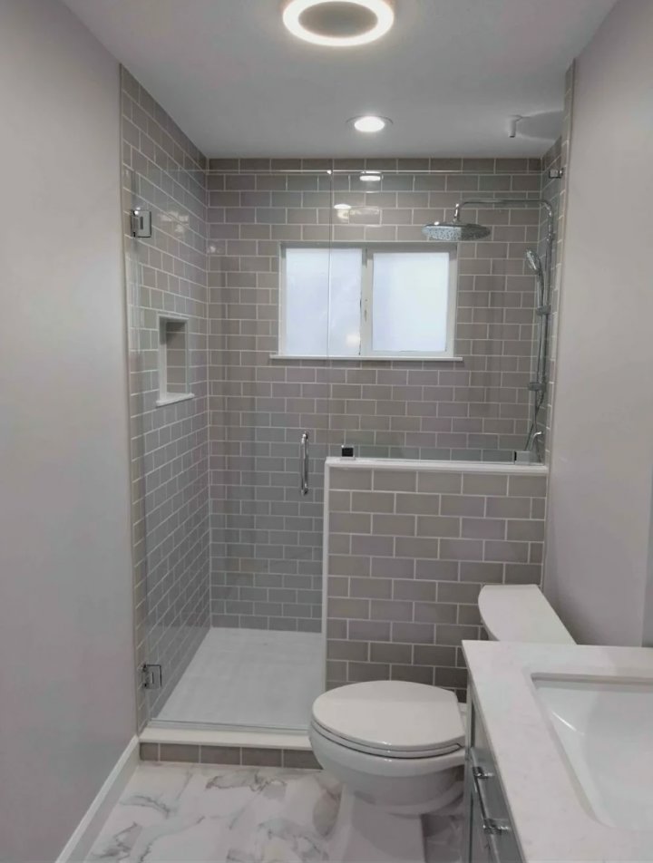 A modern bathroom remodel featuring a tiled walk-in shower, toilet, and vanity completed by McCollister Contracting LLC in New Castle, DE.