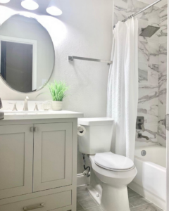 A beautifully renovated modern bathroom with new vanity, mirror, and marble-patterned shower tiles by AMG Construction Group LLC in Houston, TX.