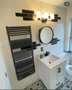 A modern bathroom renovation with black and white subway tiles, a vanity, and a towel warmer by Garrett Group Construction in Philadelphia, PA.