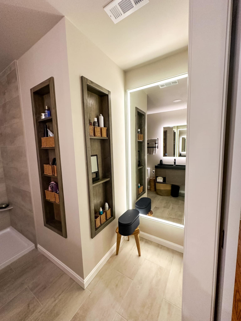 Modern bathroom renovation with built-in wooden shelves and an illuminated mirror by Blue Ribbon Renovations in Elizabethtown, KY.
