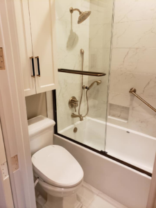 A modern bathroom renovation featuring a new toilet, bathtub, and glass shower screen installed by Kenneth C. Bergeron, Architect in Pollock, LA.