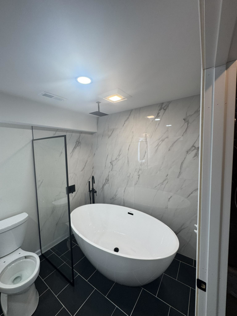 Modern bathroom renovation with a sleek freestanding tub and shower enclosure by Home Improvements by Duane in Racine, WI.