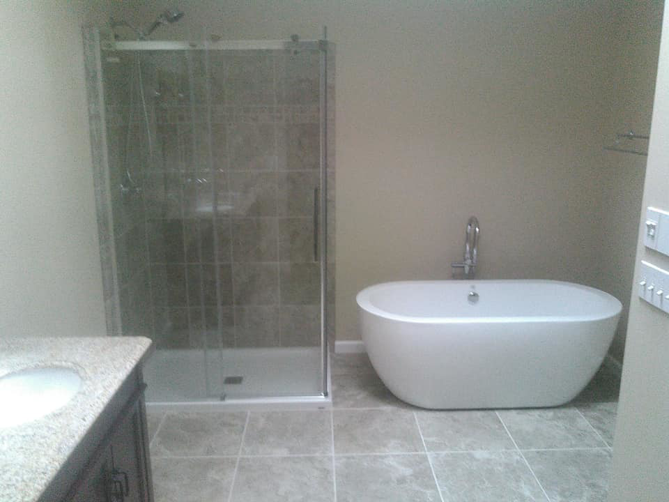 A modern bathroom renovation featuring a walk-in shower and freestanding bathtub by Paulus Contracting in Fayetteville, OH