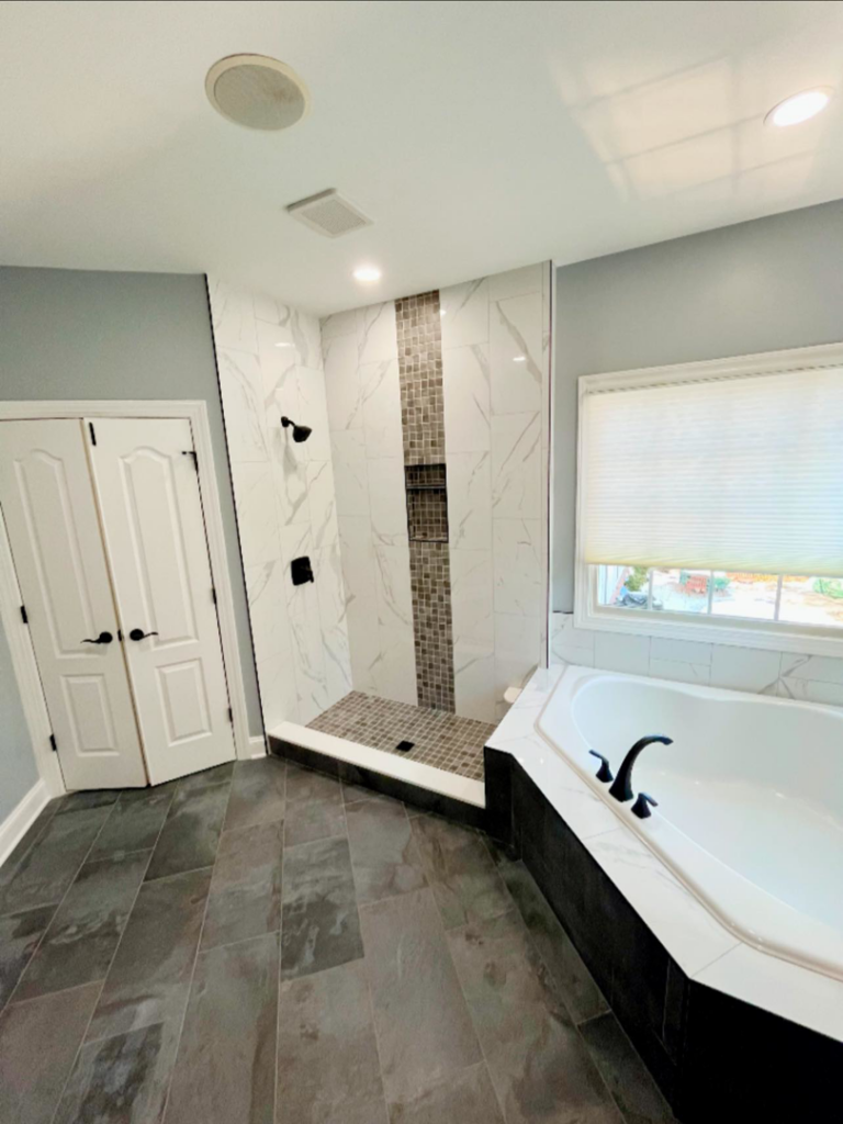 A modern bathroom renovation featuring a walk-in shower, bathtub, and dark tile flooring by Prestige Services in Annapolis, MD.