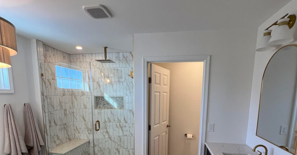 A beautifully renovated modern bathroom featuring a large tiled shower and double vanity by Rock Solid Construction in Rochester, NY