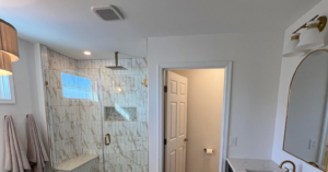 A beautifully renovated modern bathroom featuring a large tiled shower and double vanity by Rock Solid Construction in Rochester, NY