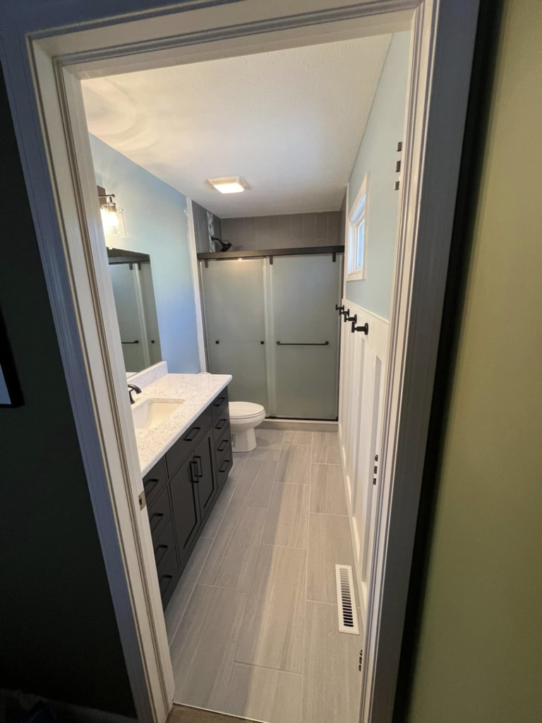 A modern bathroom renovation completed by Roempagel Renovations LLC in South Bend, IN, featuring a new vanity, toilet, and shower.