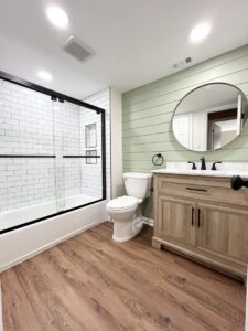 A modern bathroom renovation featuring a shower/tub combo, a new vanity, and a stylish green shiplap accent wall by RW Contracting Phila, LLC in Philadelphia, PA.
