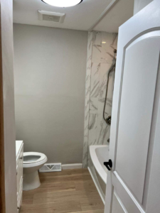 A modern bathroom renovation showcasing a new toilet, vanity, and a stylish tiled shower area by J&A Contractor LLC in Milwaukee, WI.