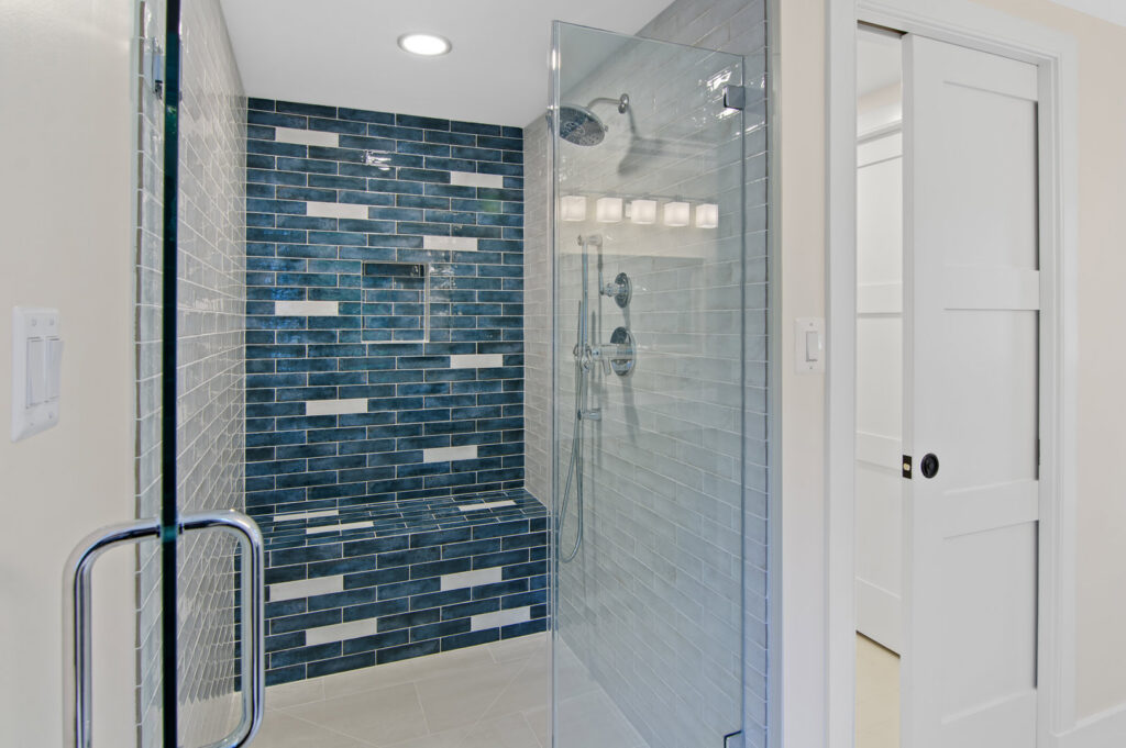 A modern bathroom shower remodel with blue and white subway tiles and a glass enclosure by Total Craftsmen in Towson, MD
