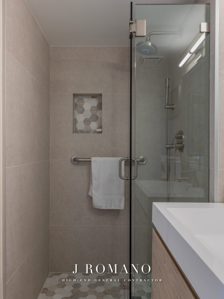 Modern bathroom shower renovation with tiled walls and glass enclosure by J Romano Group in Miami Beach, FL