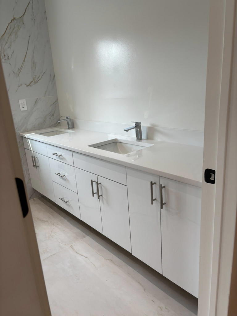 A newly installed modern bathroom vanity with double sinks and white cabinets by Golden Tile Construction in Yonkers, NY.