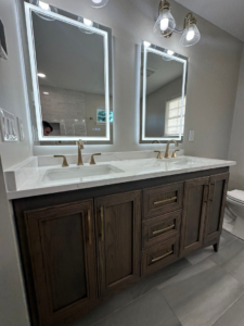 A modern bathroom vanity with double sinks and illuminated mirrors installed by Quality Work Home Services in Syracuse, NY.
